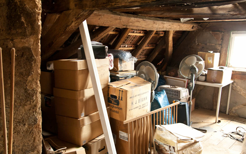 a cluttered attic with cardboard boxes, among other things
